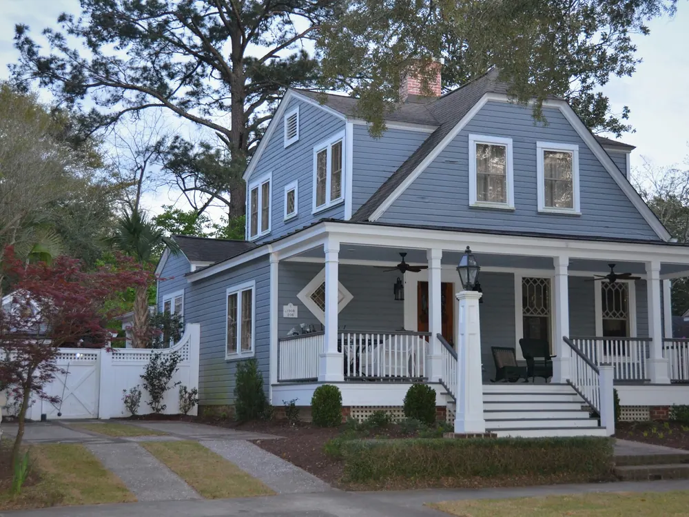 Blue two-story house with a wide white front porch on a neighborhood street